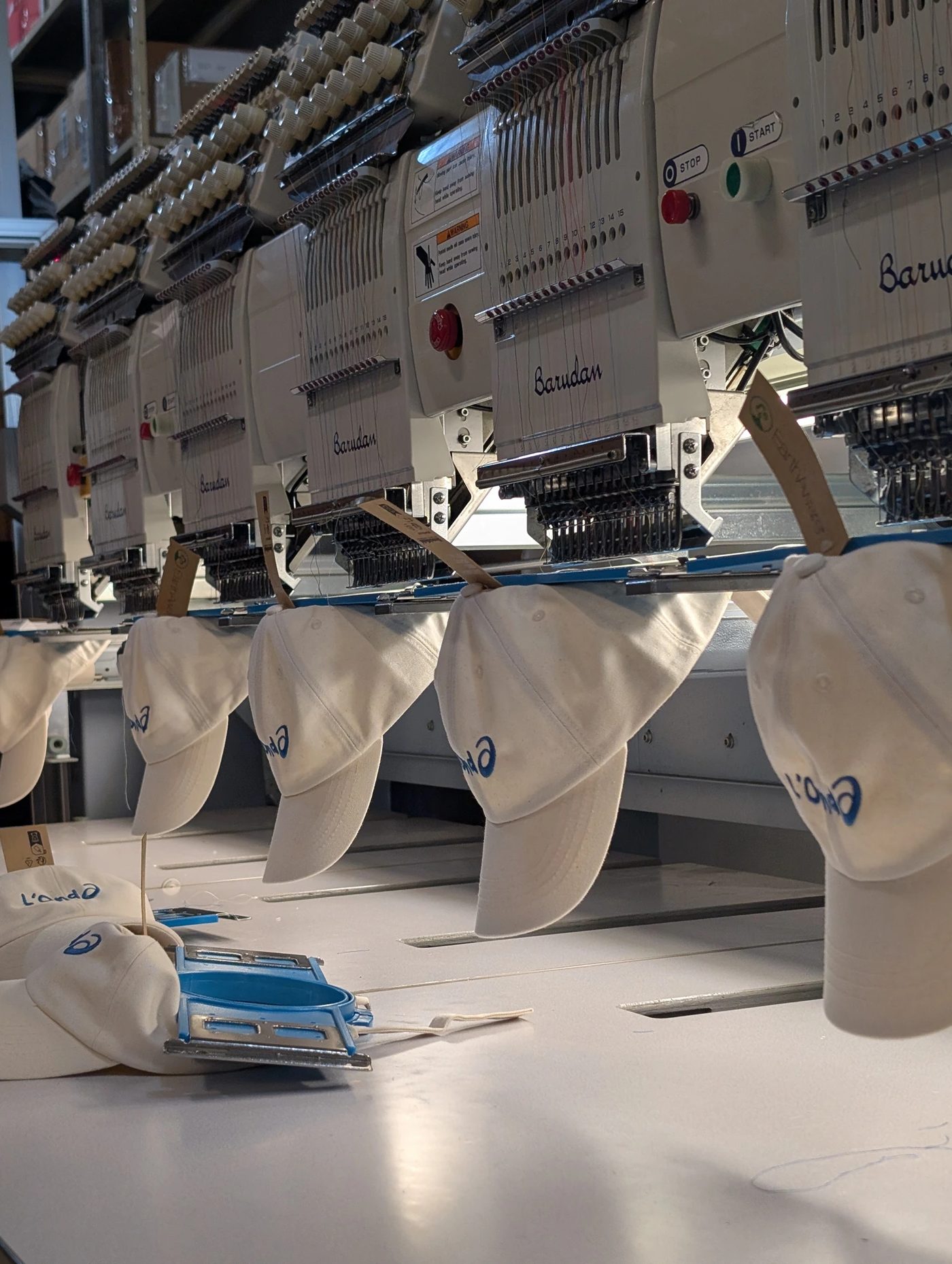 Rangée de brodeuses multi-têtes de l'atelier brodant une série de casquettes