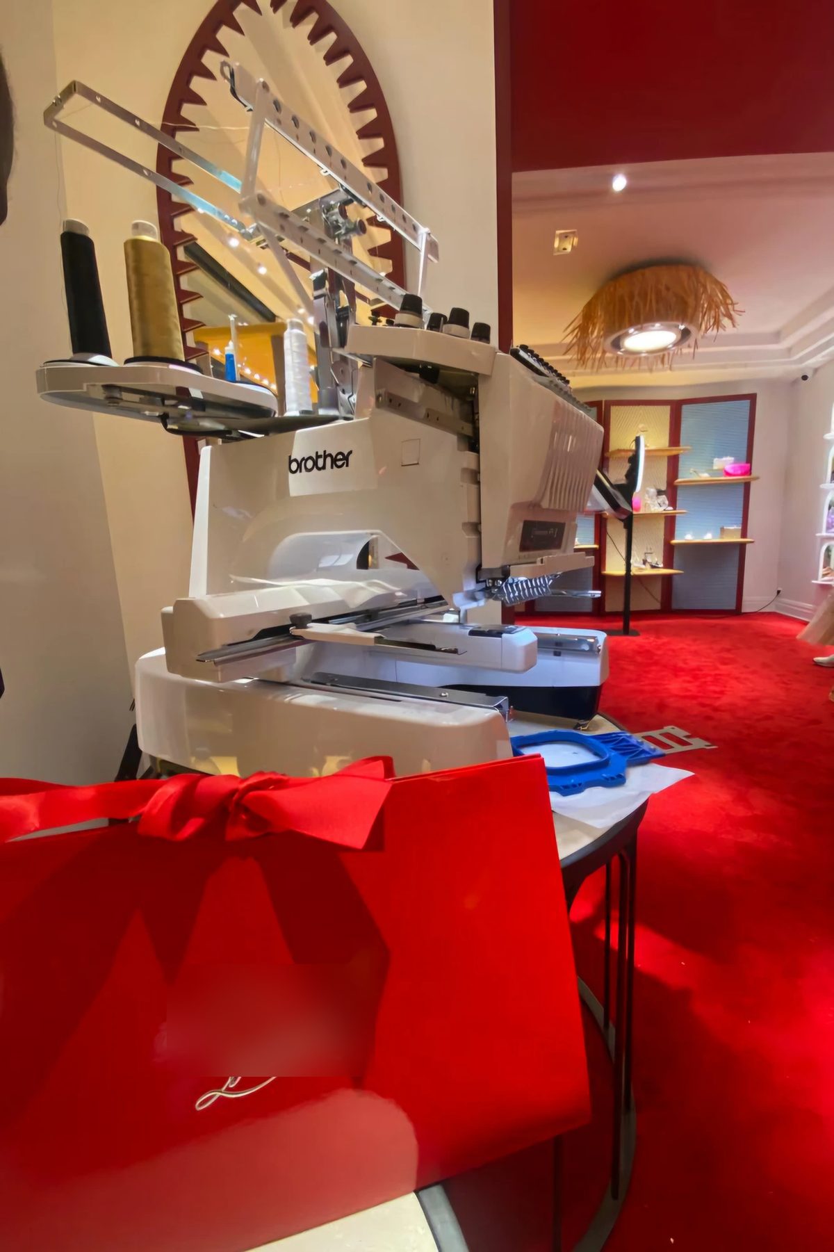 Brodeuse installée dans une boutique de luxe au tapis rouge pour une animation de personnalisation en direct